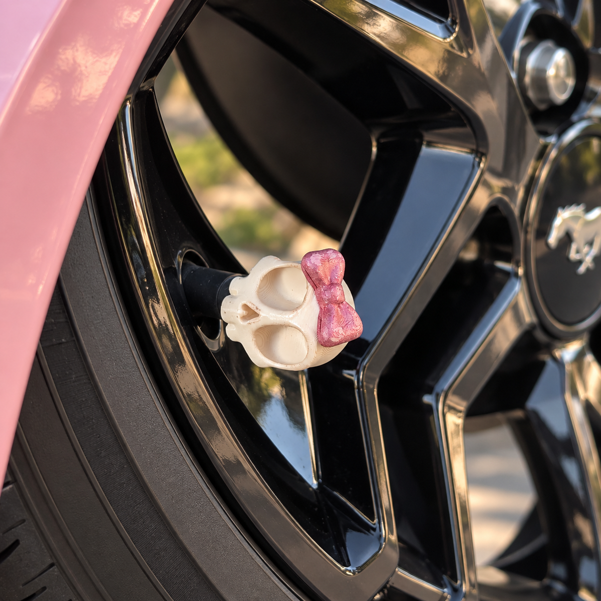 Styled color preview: cream skull valve cap with a pink bow on a black wheel beside blush-pink bodywork