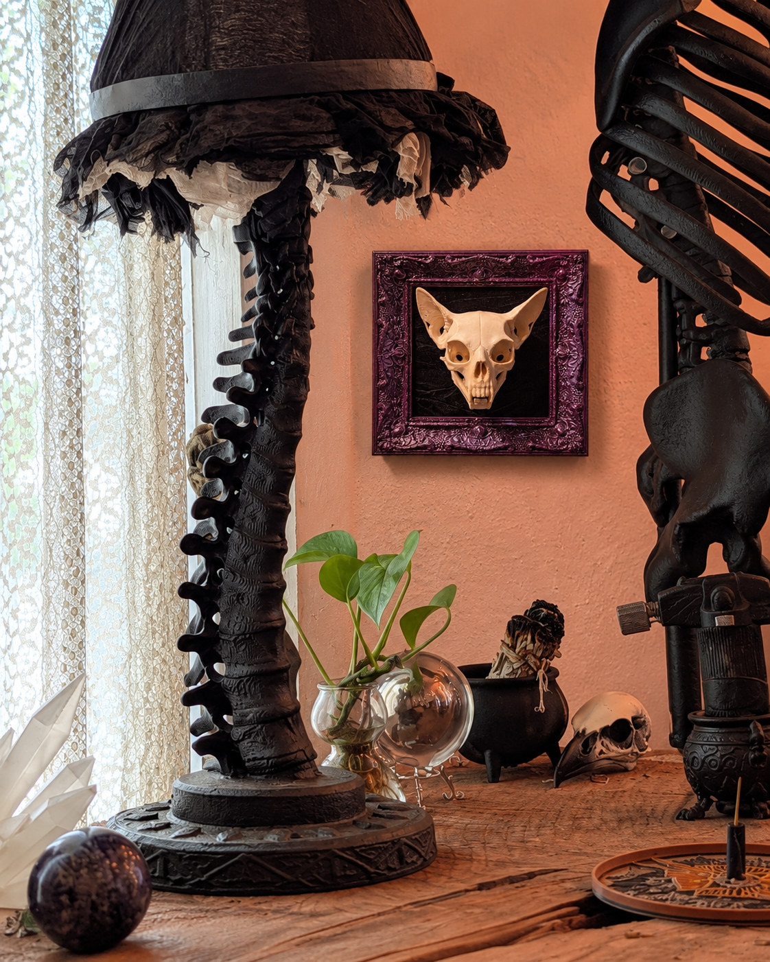 Feline skull in plum frame beside the Gothic Rose Gallery window — AI-assisted room staging.