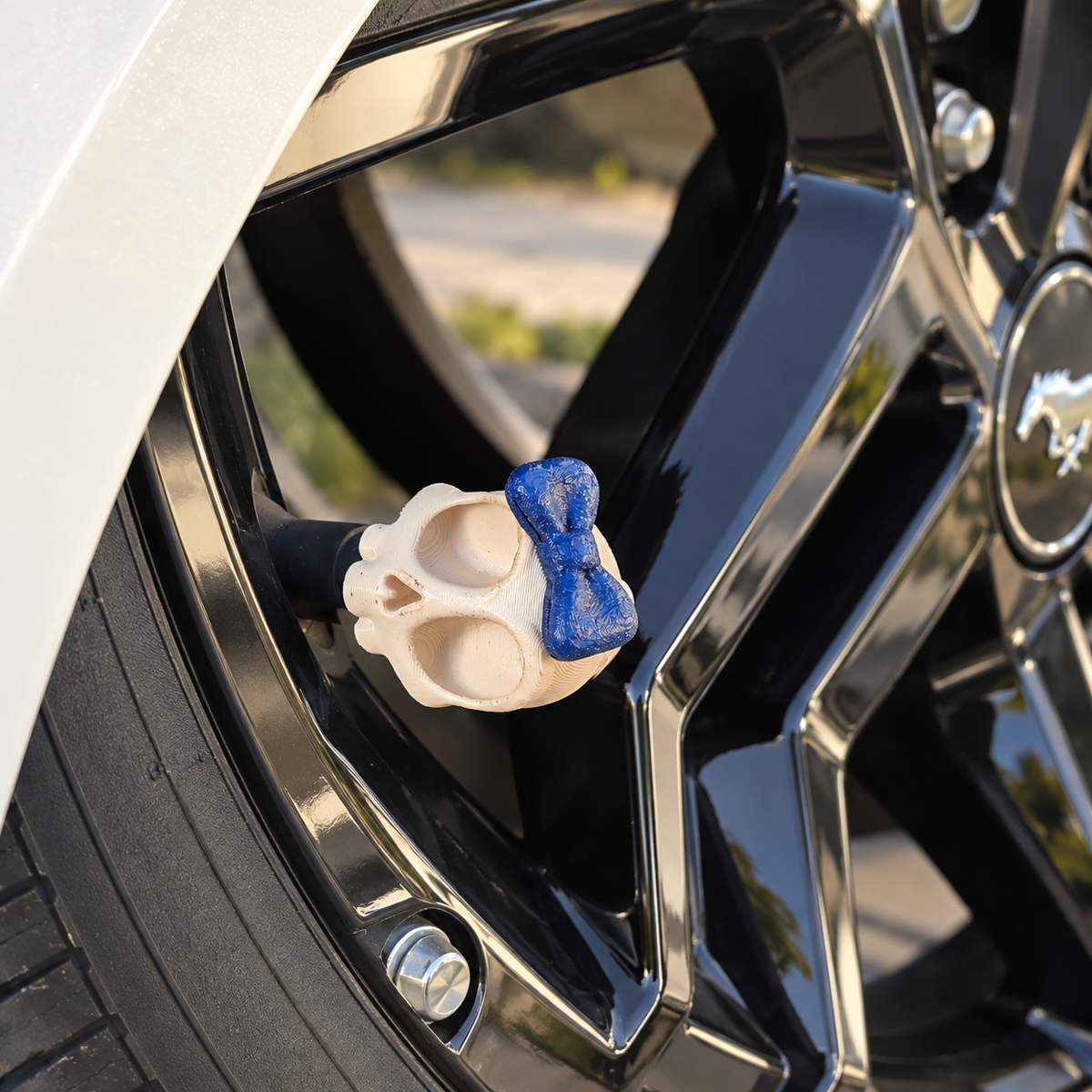 Styled color preview: cream skull valve cap with a blue bow on a black wheel beside pearl-white bodywork