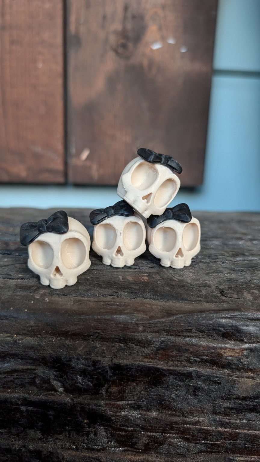 Four cream skull valve caps with black bows, sold as one set