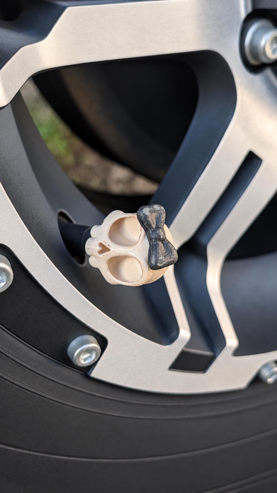 Retained Etsy photograph of a cream skull valve cap with a black bow installed on a silver and black rim.